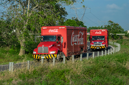 Catemaco, Mexico - 31 December, 2018: Coca-Cola trucks (Kenworth and International trucks) driving on the road. These models are popular trucks in North America.