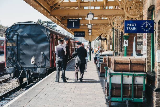 Sheringham, UK - April 21, 2019: Staff talking on platform next to The Poppy Line steam train, also known as the North Norfolk Railway, a Heritage Steam Railway that runs from Sheringham to Holt.
