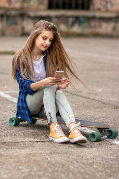 istock Female Skateboarder is Using a Mobile Phone in the Street 1145714356