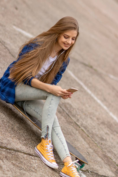 istock Female Skateboarder is Using a Mobile Phone in the Street 1145714398