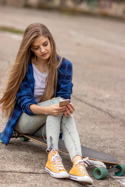 istock Female Skateboarder is Using a Mobile Phone in the Street 1145714413