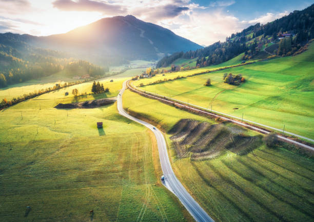 Aerial view of the road in mountain valley at sunset in summer in Dolomites, Italy. Top view of asphalt roadway, railroad, hills with green meadows, blue sky, trees, buildings. Highway and fields Aerial view of the road in mountain valley at sunset in summer in Dolomites, Italy. Top view of asphalt roadway, railroad, hills with green meadows, blue sky, trees, buildings. Highway and fields rail car stock pictures, royalty-free photos & images