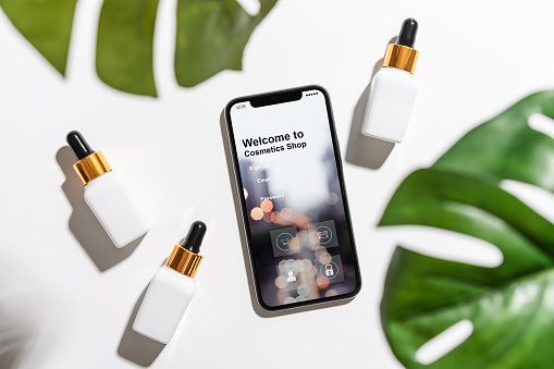 Design of the smartphone screen, Application of cosmetics online. White serum bottle and cream jar, mockup of beauty product brand. Top view on the white background.