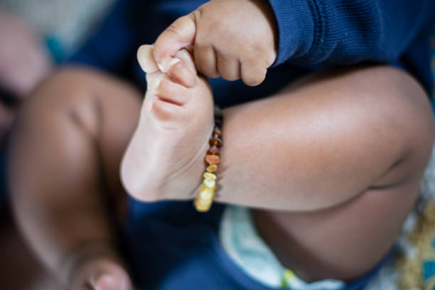 Toes Baby wearing an amber anklet, holding on to it’s toes. baby bracelet stock pictures, royalty-free photos & images
