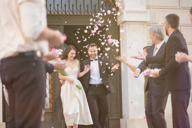 istock Guests throwing rose petals on bride and groom 1145724977