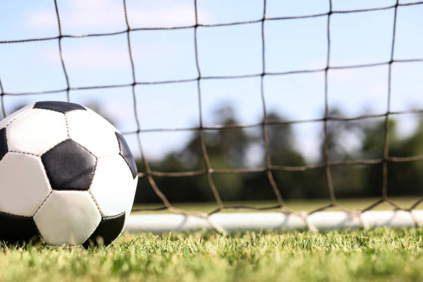 istock Soccer ball in goal net on stadium field on school campus. 1145729061