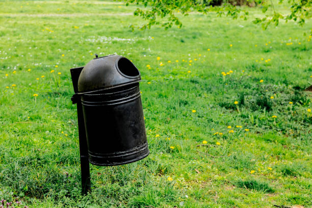 istock Black metal tresh bin on green grass. 1145752655