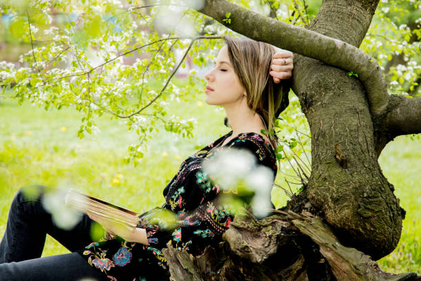 istock woman with book in springtime park. 1145754186