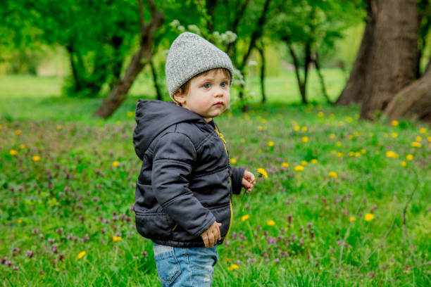 istock boy in jacket and hat in spring time park 1145754288