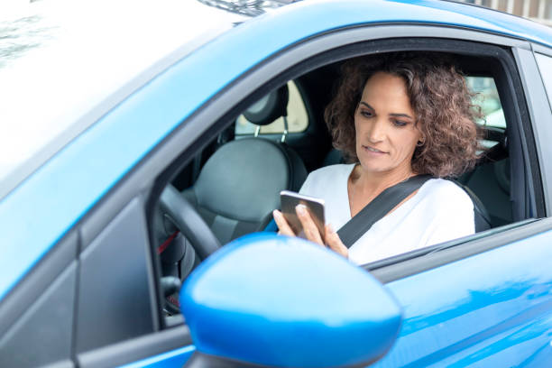 зрелая женщина текстовых сообщений по телефону в автомобиле - mobile phone seat belt text messaging smiling стоковые фото и изображения