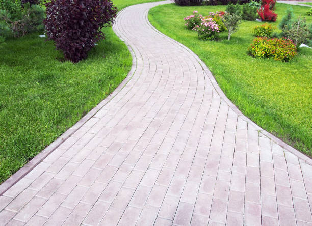 istock Curved footpath paved with bricks running ahead along a green grassy lawn. Landscaping design 1145764389