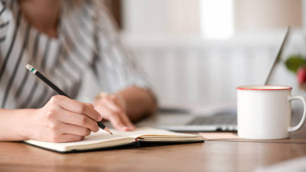 istock Closes up woman hand is writing on notepad with pen in office. 1145765603