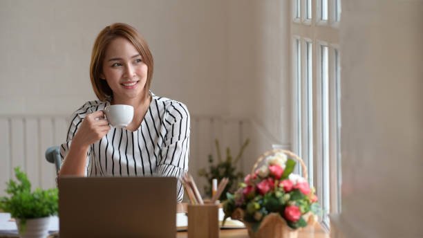 istock Coffee break at work, Asian businesswoman drinking coffee at office 1145766317