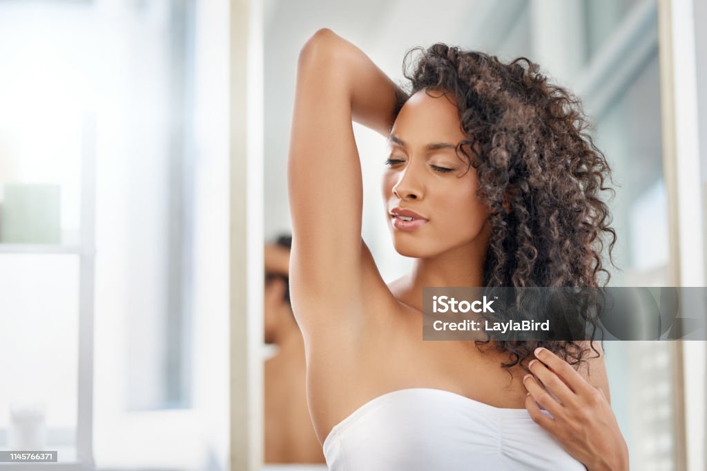 Because body odour should be the least of your concerns Shot of an attractive young woman smelling her armpits during her morning beauty routine Women Stock Photo
