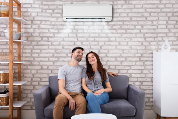 istock Couple Sitting On Couch Under Air Conditioner 1145767022