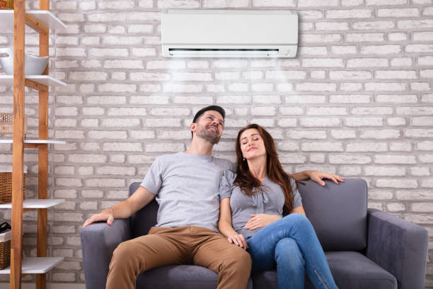 istock Couple Sitting On Couch Under Air Conditioner 1145767028