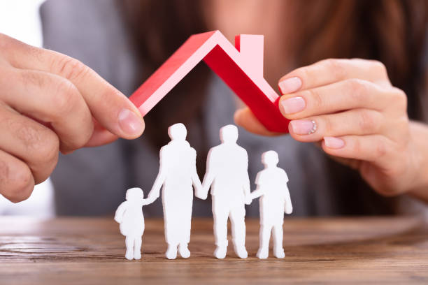 istock Couple Protecting Family Figures With Roof 1145767057
