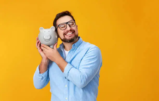 Photo of concept of Finance and business.  man with  piggy Bank on  yellow background color