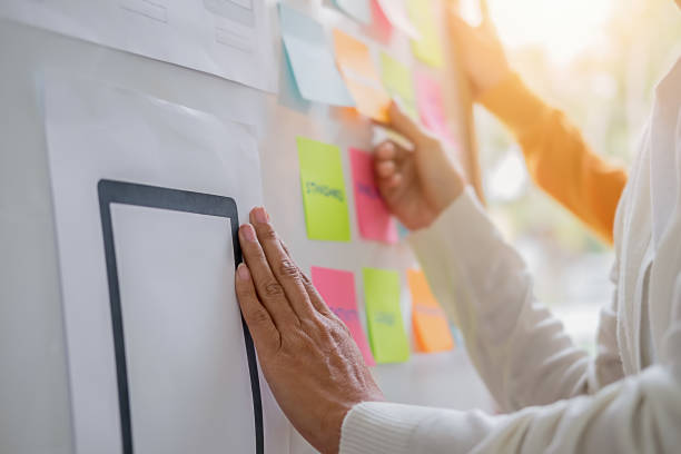 istock Web designer brainstorming for a strategy plan. Colorful sticky notes with things to do on office board. User experience (UX) concept. 1145769335