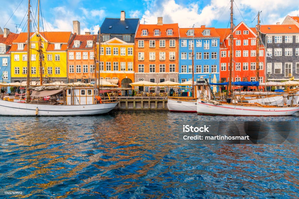 Nyhavn area of popular bar and restaurant at beautiful blue sky, with colorful facades of old houses and old ships in the Old Town of Copenhagen, capital of Denmark. Nyhavn Stock Photo