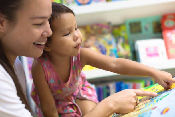 matka i dziecko szukają razem książek obrazkowych. czas rodzinny. - baby book toddler reading zdjęcia i obrazy z banku zdjęć