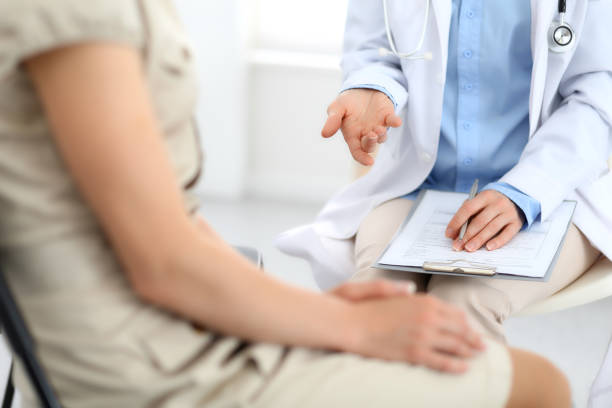 istock Doctor and patient talking. Physician at work in hospital while writing up medication history records form on clipboard near sitting woman. Healthcare and medicine concepts 1145771989