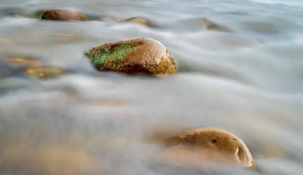 Water rushing down a mossy rock in a river.