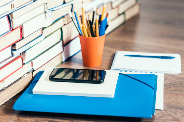 istock Stack of books, hardback books, smartphone, plastic folder, notebook and pencils on wooden table copy space for text 1145776885