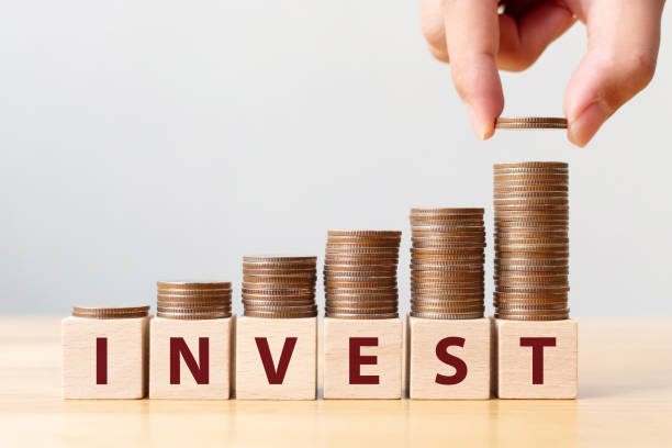 istock Hand putting coins on stack stair as step growing growth and wooden cube block with word INVEST. Investment and save money concept 1145778785