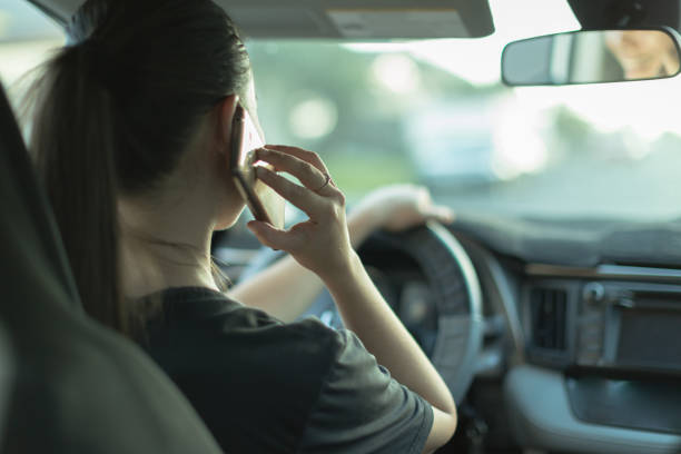 Distracted woman talking on her phone while driving. stock photo