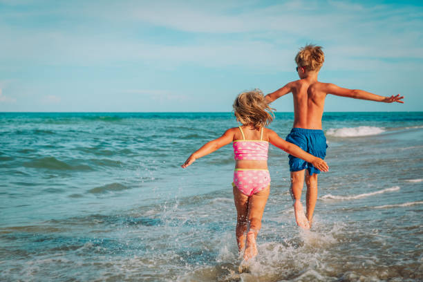 little girl and boy run fly play with waves on beach vacation