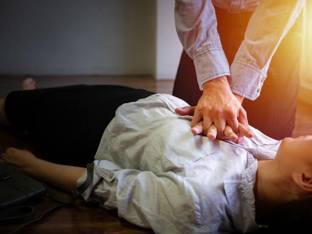 homme de bureau bénévole utiliser la pompe à main sur la poitrine pour secourisme d’urgence cpr sur la femme de crise cardiaque inconscient, essayer de réanimation patiente femme au travail - human cardiopulmonary system photos et images de collection