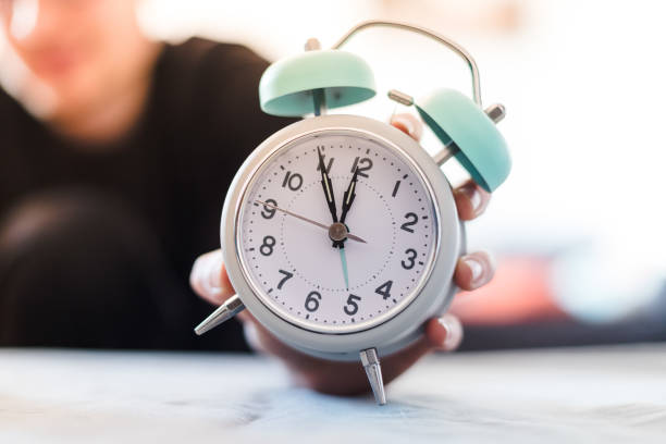 istock Man is holding an alarm clock in the hand, blurry background 1145800432