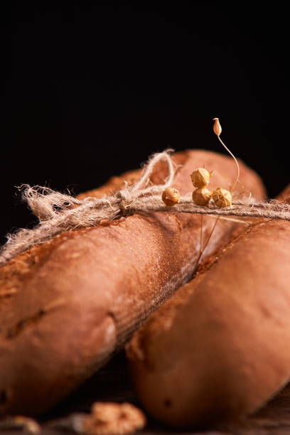 istock Two Fresh baguettes on dark wooden table. Selective focus 1145805571