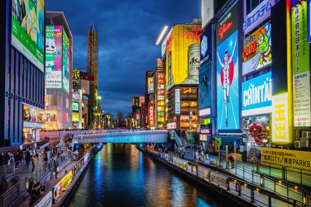 Crowded Dotonbori bridge over water canal with illuminated signs and billboards , long exposure, motion blurred crowd at Night. Unrecognizable Crowd. Dotonbori, Osaka, Japan, Asia.