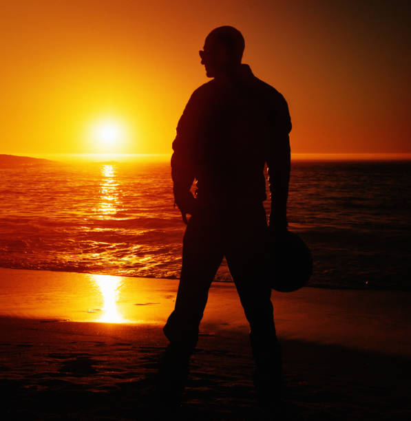 istock Silhouetted motorcyclist admires beautiful seaside sunset 1145807320