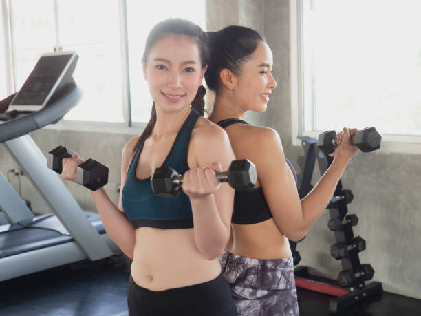 istock two woman is exercising with a dumbbell in gym 1145811228