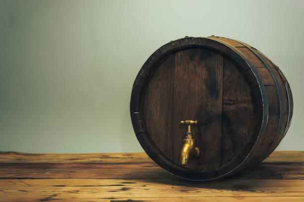 istock Wooden barrel with tap on a old oak table. Gray background behind. 1145812180