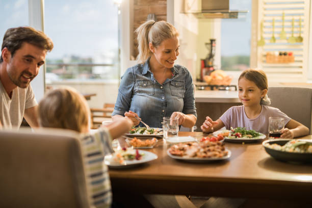 istock Happy family enjoying while having lunch together at dining table. 1145812193
