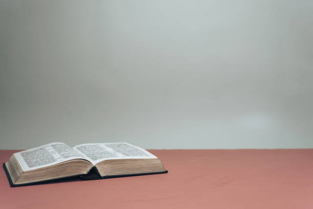istock Open Holy Bible on a red table.  Grey wall background. 1145812519