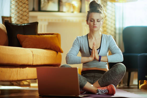 istock woman meditating using online yoga training program in laptop 1145815483