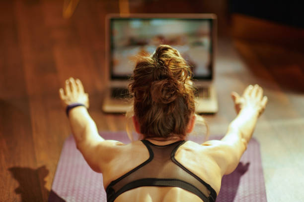woman watching fit tutorial on internet while doing exercises - www computer monitor internet photography imagens e fotografias de stock