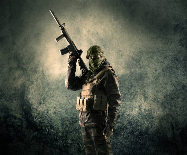 retrato de un soldado enmascarado fuertemente armado con fondo grungy - terrorism fotografías e imágenes de stock