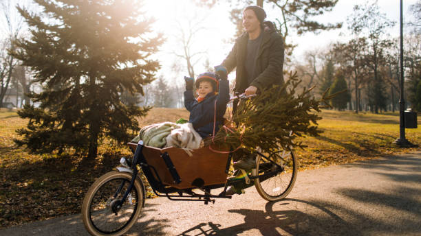 Daddy and son in Christmas adventure Father and son riding their Christmas tree by cargo bike cargo bike photos stock pictures, royalty-free photos & images