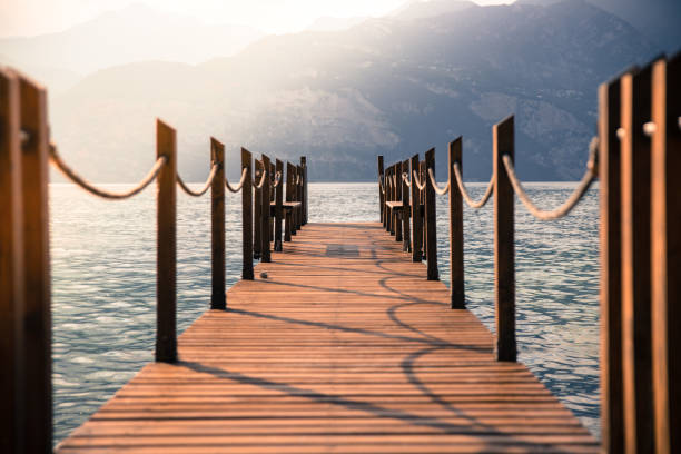 istock Summer holiday: Wooden dock pier over blue lake water. Cloudy evening scenery. 1145821080