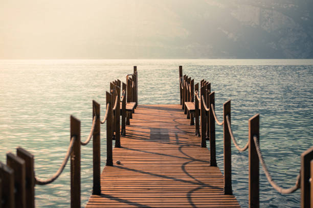 istock Summer holiday: Wooden dock pier over blue lake water. Cloudy evening scenery. 1145821142