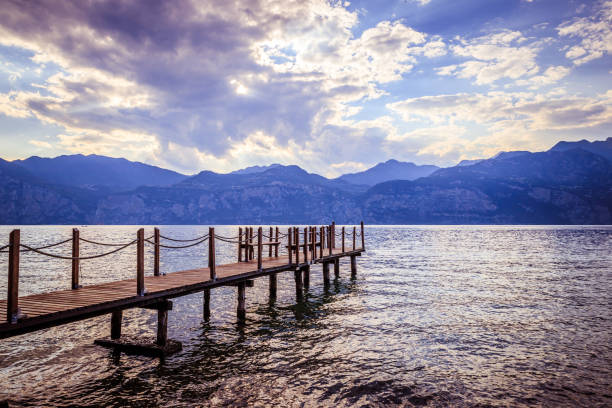 istock Summer holiday: Wooden dock pier over blue lake water. Cloudy evening scenery. 1145821308
