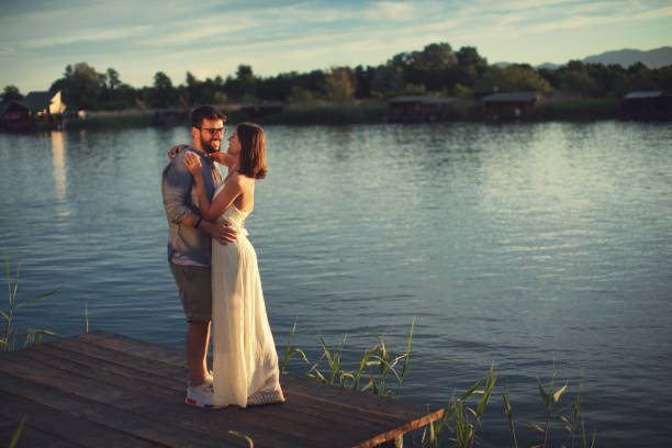 istock Young couple in love flirting by the river at sunset 1145821966