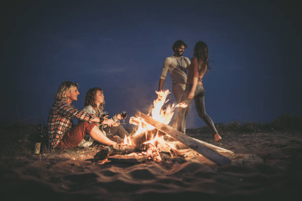 istock Happy couples having fun on a night party at the beach by the campfire. 1145831022