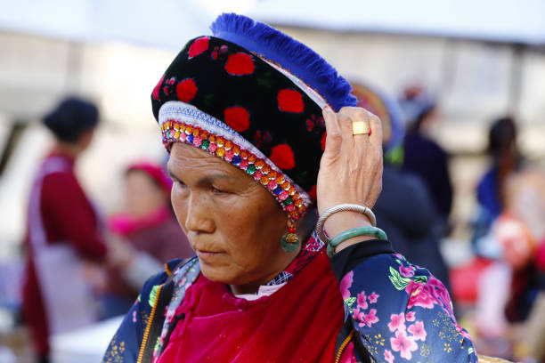 a woman of an ethnic minority of yunnan with her traditional clothes in the market of zhoucheng village, dali, yunnan, china - hani imagens e fotografias de stock